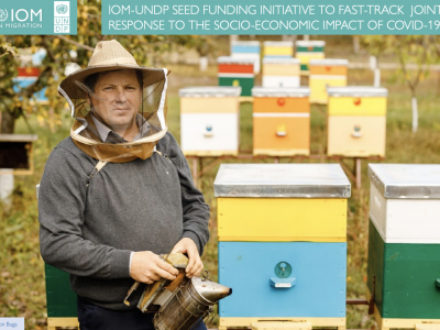 An image of a beekeeper standing next to his beehives
