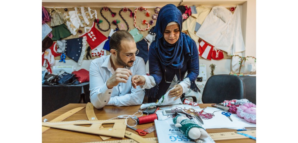 An image of a woman assisting a man with in a sewing class for men