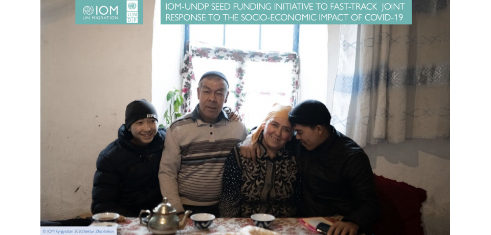 An image of a Kyrgyz family seated together around a table and smiling