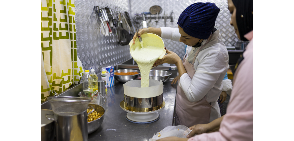 A woman baker pours cake batter into a tin at her business