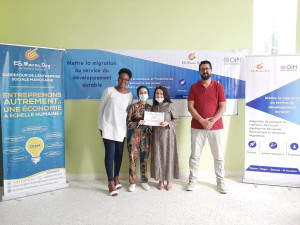Image of three women and a man standing and smiling to the camera. The two women in the middle are holding a certificate.