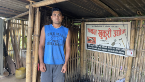 a young man in blue shirt standing in a bamboo shack