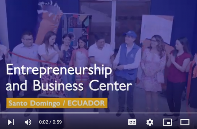 Video still with a line of people cutting a ribbon to open a new center and the words "Entrepreneurship and business center: Santo Domingo, Ecuador"