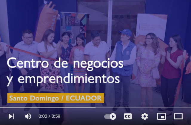 Fotograma de vídeo con una fila de personas cortando una cinta para inaugurar un nuevo centro y las palabras "Centro de emprendimiento y negocios: Santo Domingo, Ecuador"