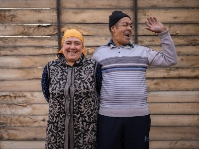 An image of a Kyrgyz man and woman smiling together outside their home