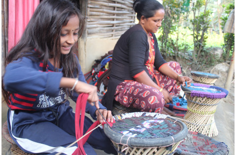 A woman and a girl are weaving with smile on their face