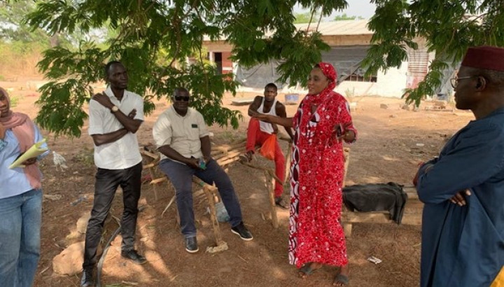 A woman and several men are talking at a farm