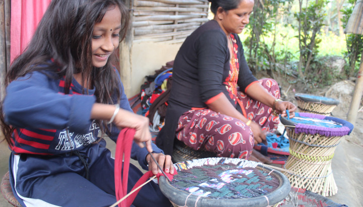 A woman and a girl are weaving with smile on their face