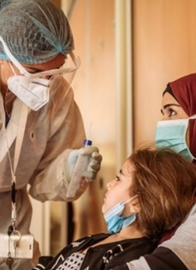 Image of masked woman medical worker talking to mother and child