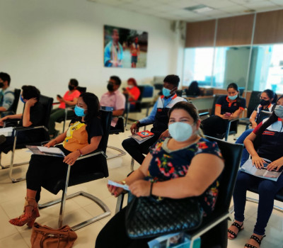 A group of people wearing masks and sitting in a meeting room
